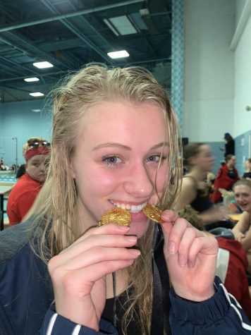 Lasecki bites both of her gold medals after winning the 200 IM and the 100 fly. Photo by @bpgirlsswimming on twitter